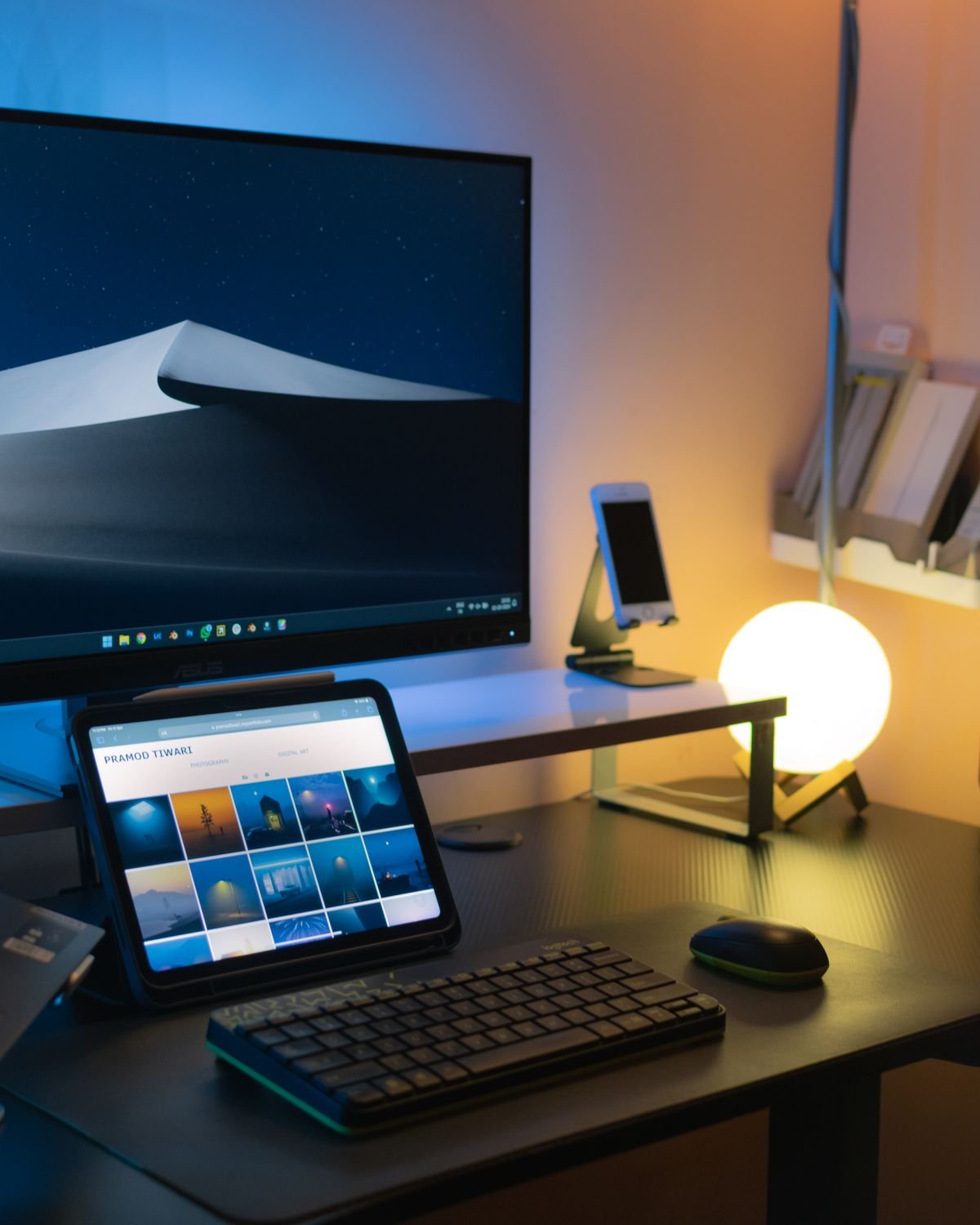Stylish desk setup with monitor, tablet, keyboard, and ambient lighting
